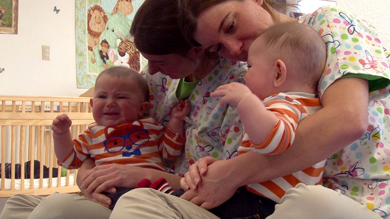 A staff member and an infant sit by a mirror