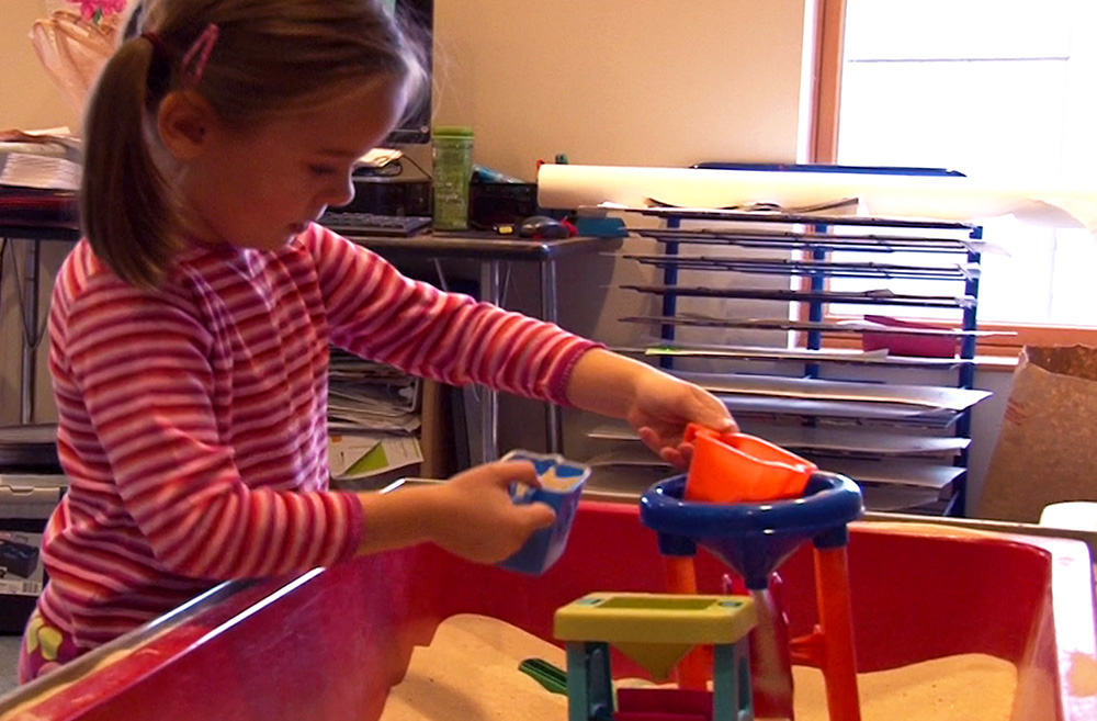 A girl learns while playing in a sensory table